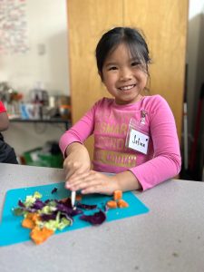 A FoodPrints student chops vegetables for a recipe