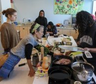 Teachers gather in a kitchen classroom to workshop recipes for their FoodPrints students