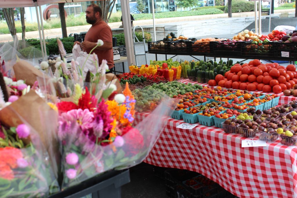 flowers in foreground, tables filled with produce in the background